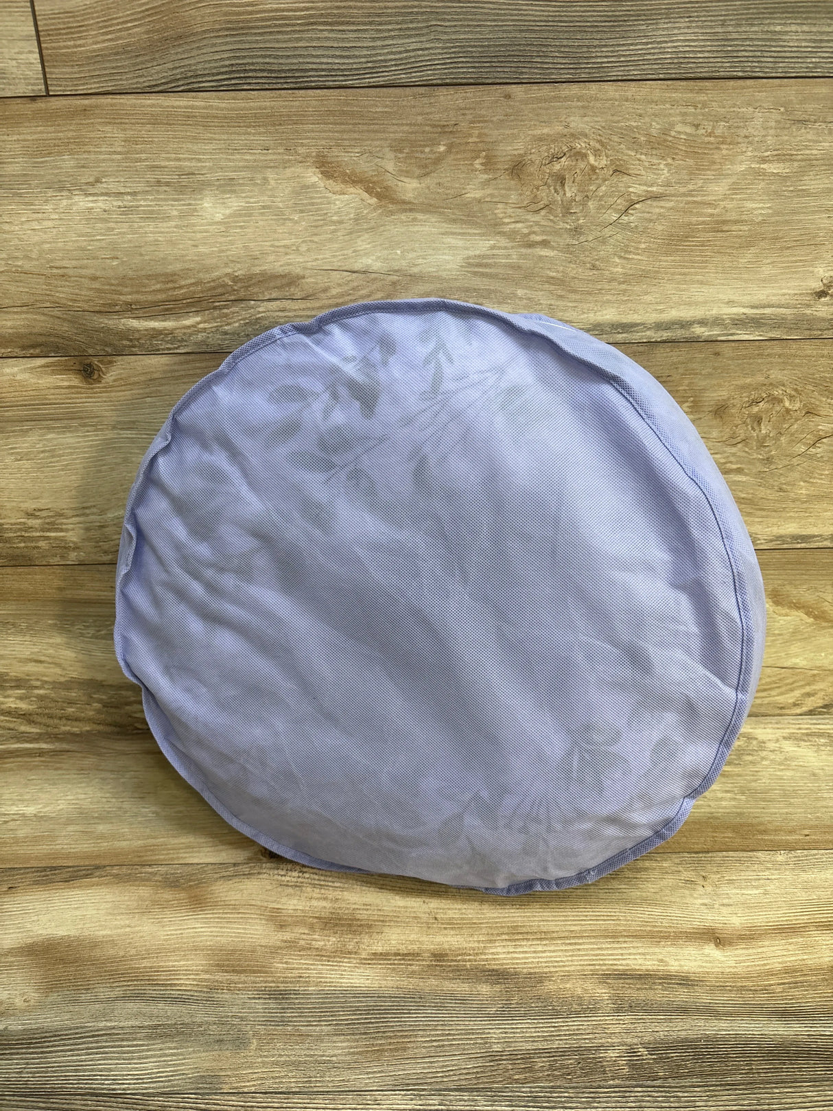 Top-down view of Boppy nursing pillow showcasing light purple slipcover and wrinkled fabric on a wood plank background
