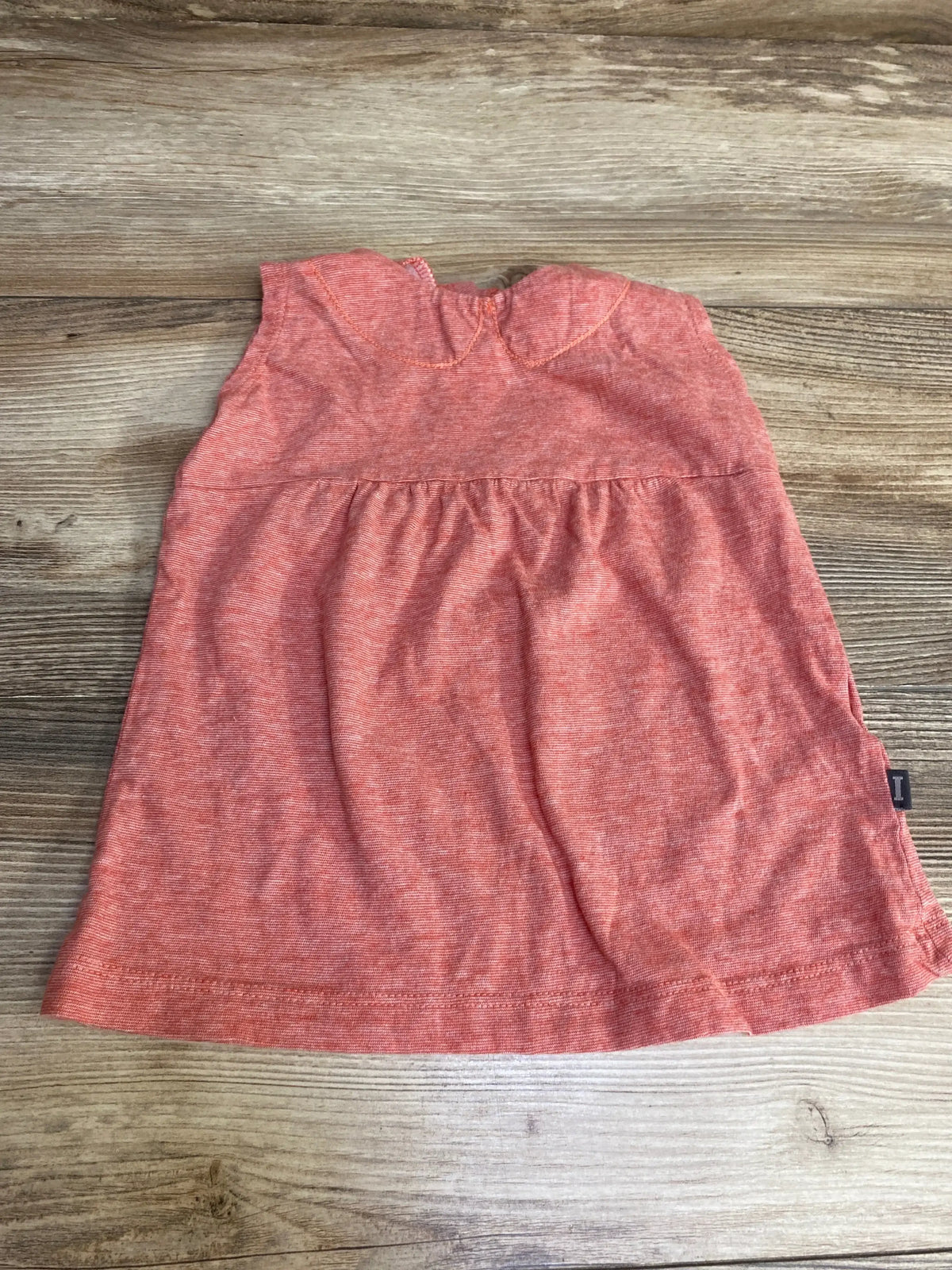 Flat lay of red sleeveless Imps and Elf baby dress showcasing Peter Pan collar and gathered waist on wood background