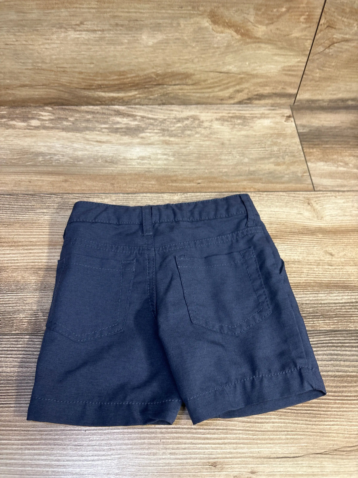 Rear view of Cat & Jack Quick Dry Chino Shorts in navy showing two back pockets and belt loops on a wood surface