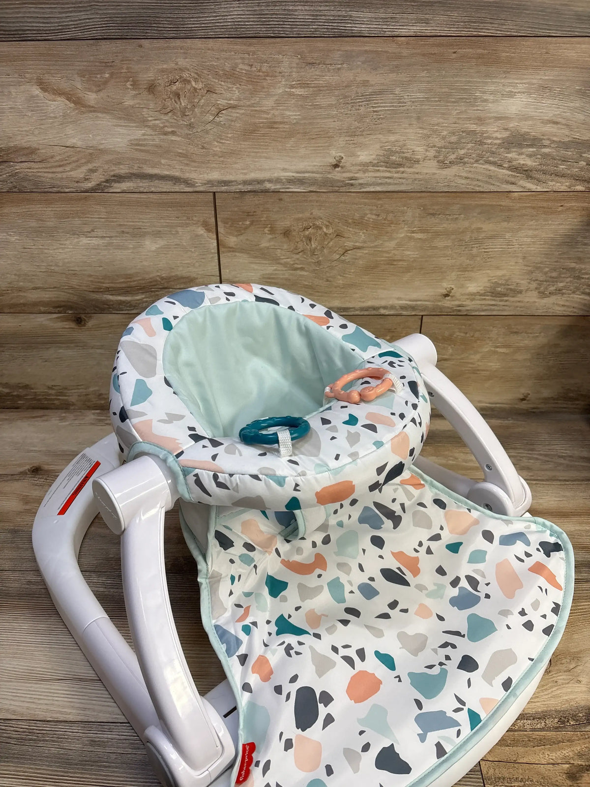 Three-quarter view of Fisher Price Sit-Me-Up Floor Seat in Pacific Pebble showing patterned seat and two removable toys