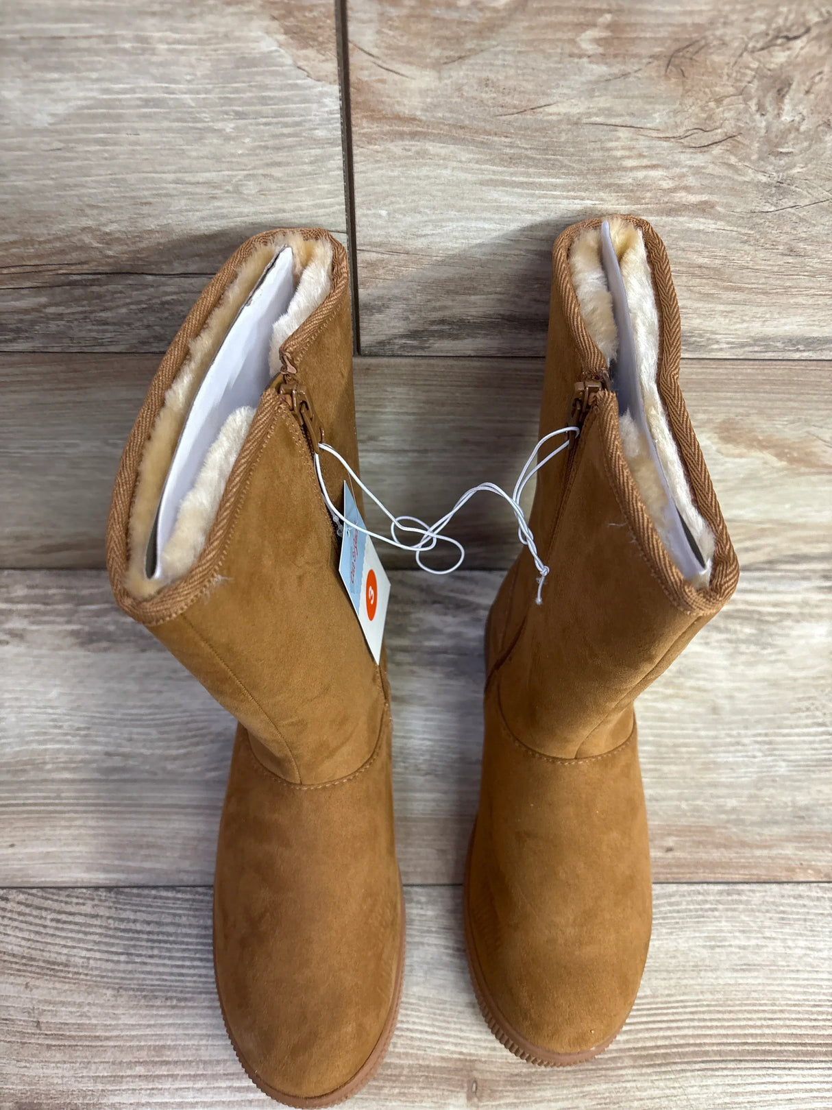 Brown suede kids boots with side zippers and shearling lining on wood floor