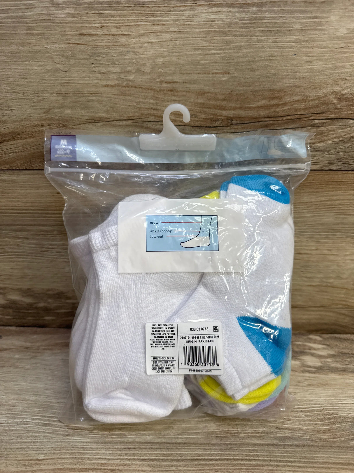 Front view of Cat & Jack low-cut kids’ socks 10-pack showing white socks with assorted colored toes and heels in a clear hanger bag on a wooden background
