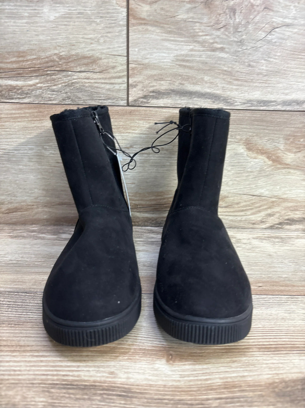 Pair of black toddler winter boots with side zipper and fuzzy lining on wooden floor