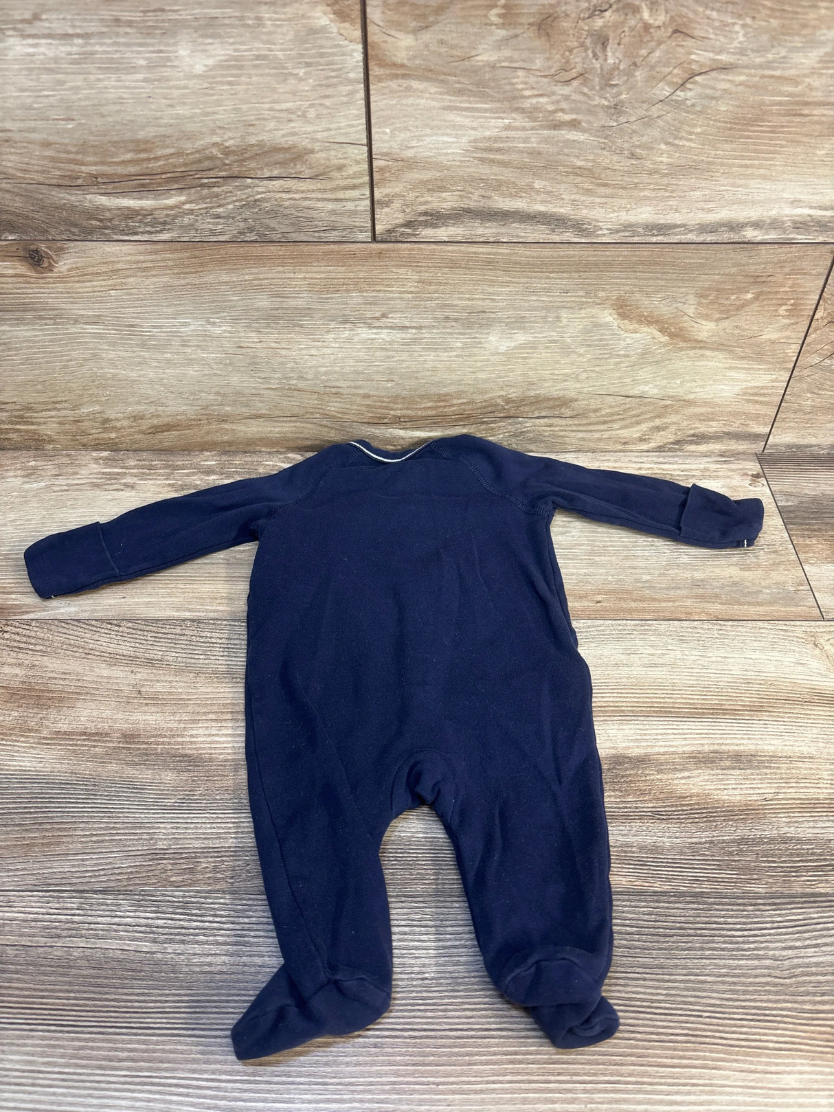 Navy blue footed baby sleeper with long sleeves on wood background, gently used infant clothing