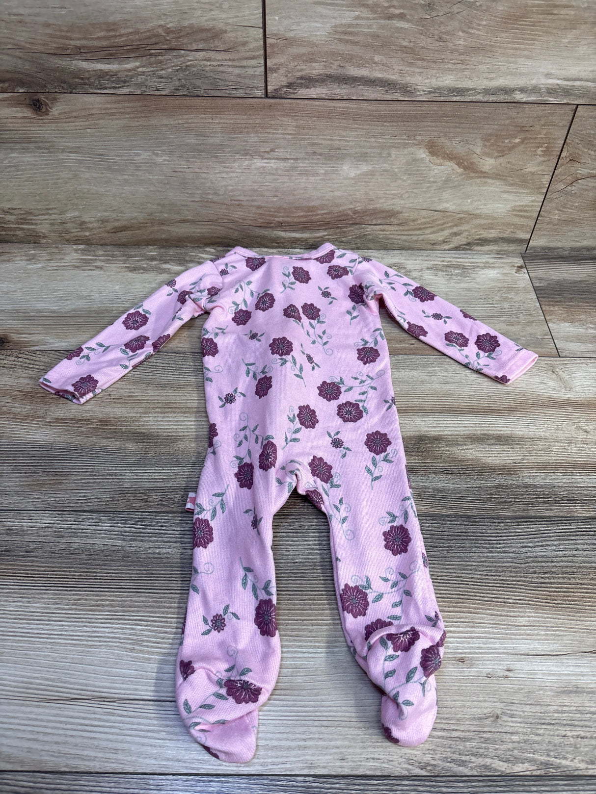 Flat lay of Millie & Myles pink footed sleeper showcasing purple floral print and long sleeves on wood background
