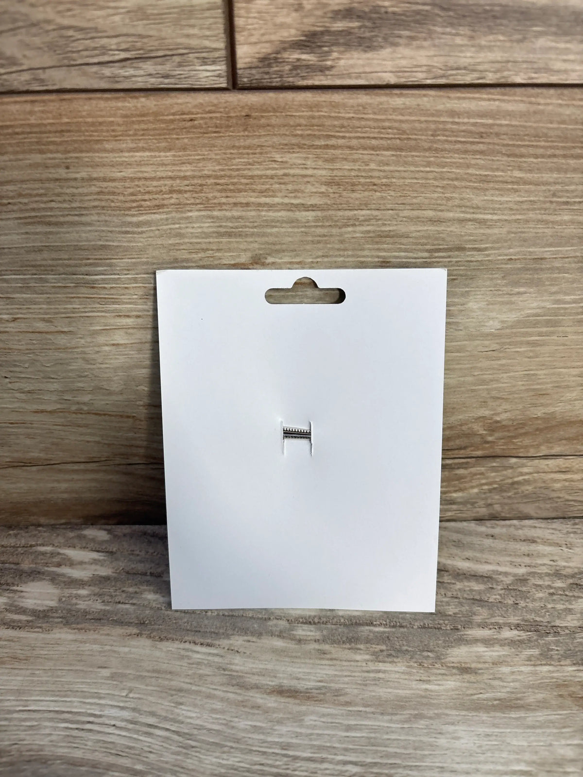 Back view of a light blue hair bow attached to a white cardboard display card.