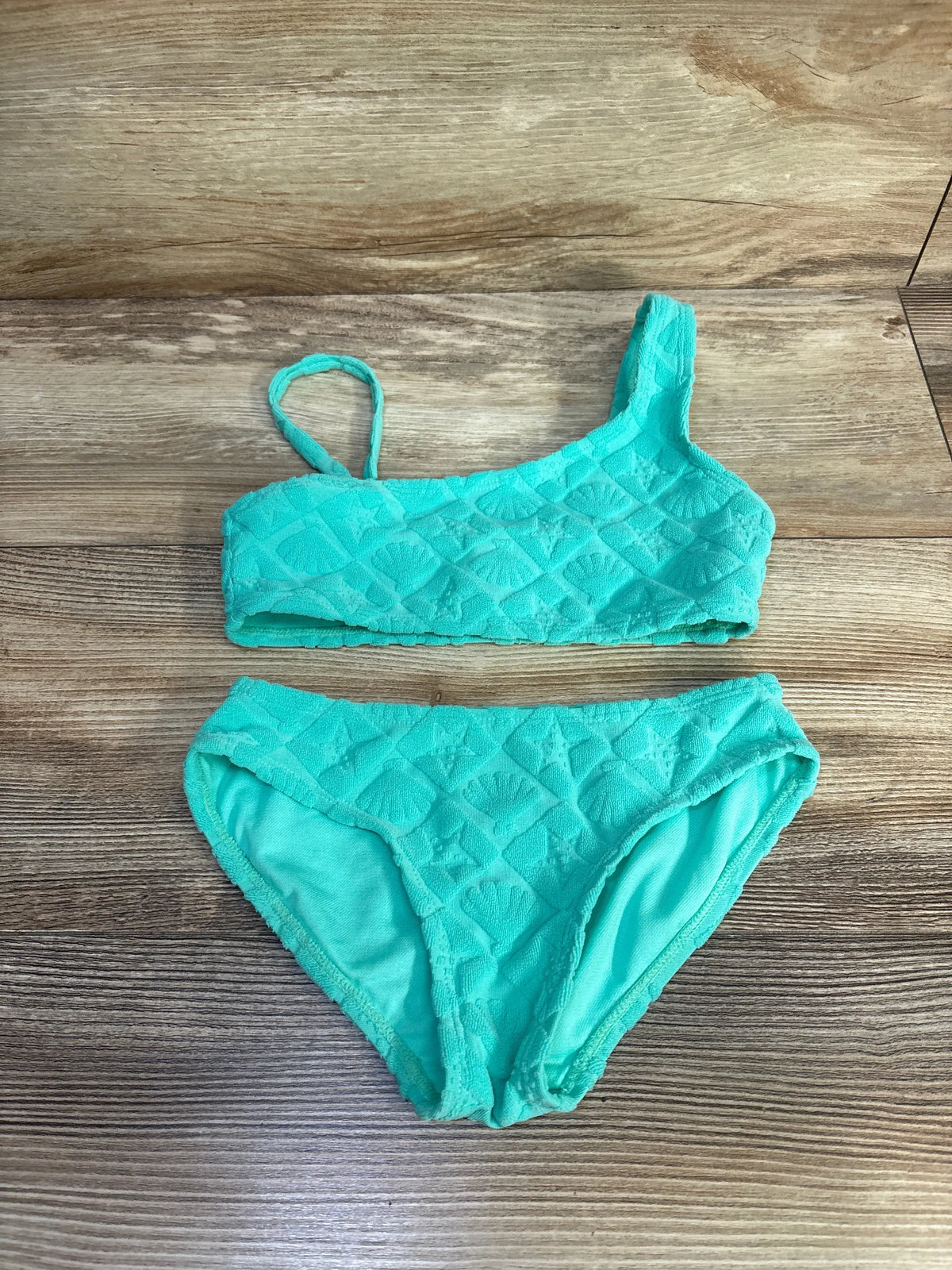 Flat lay of Cat and Jack teal two-piece terry cloth swimsuit set showcasing textured top and matching bottoms on wood