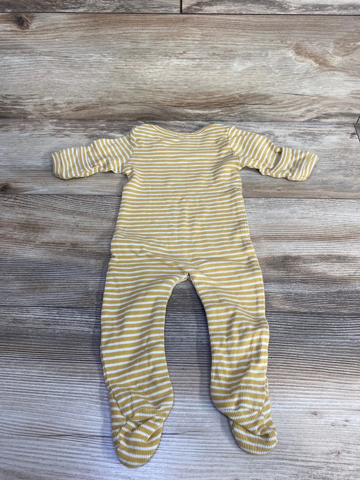 Yellow and white striped long-sleeve baby onesie with feet laid flat on wooden surface