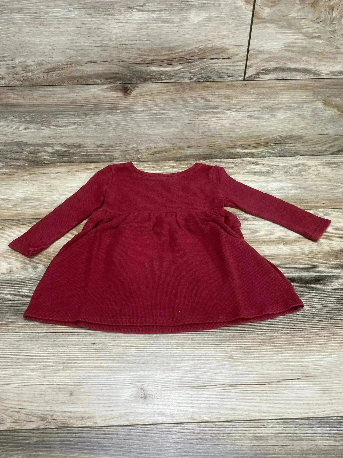 Flat lay of Old Navy toddler red thermal dress showing long sleeves and gathered skirt on wood plank background