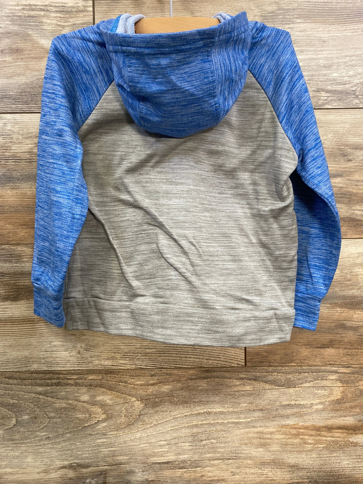 Back view of blue and gray color block hoodie on wooden surface