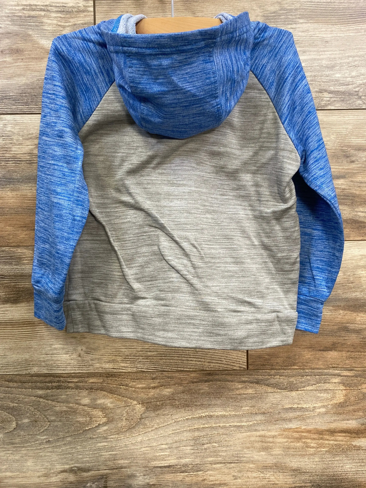 Back view of blue and gray color block hoodie on wooden surface