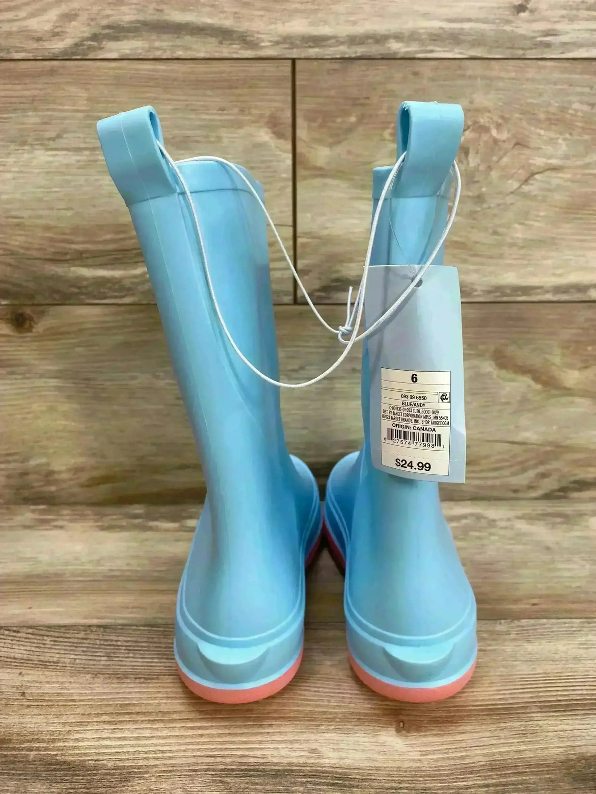 Rear view of Cat & Jack kids light blue slip-on rain boots showcasing pull tabs and pink soles on wood background
