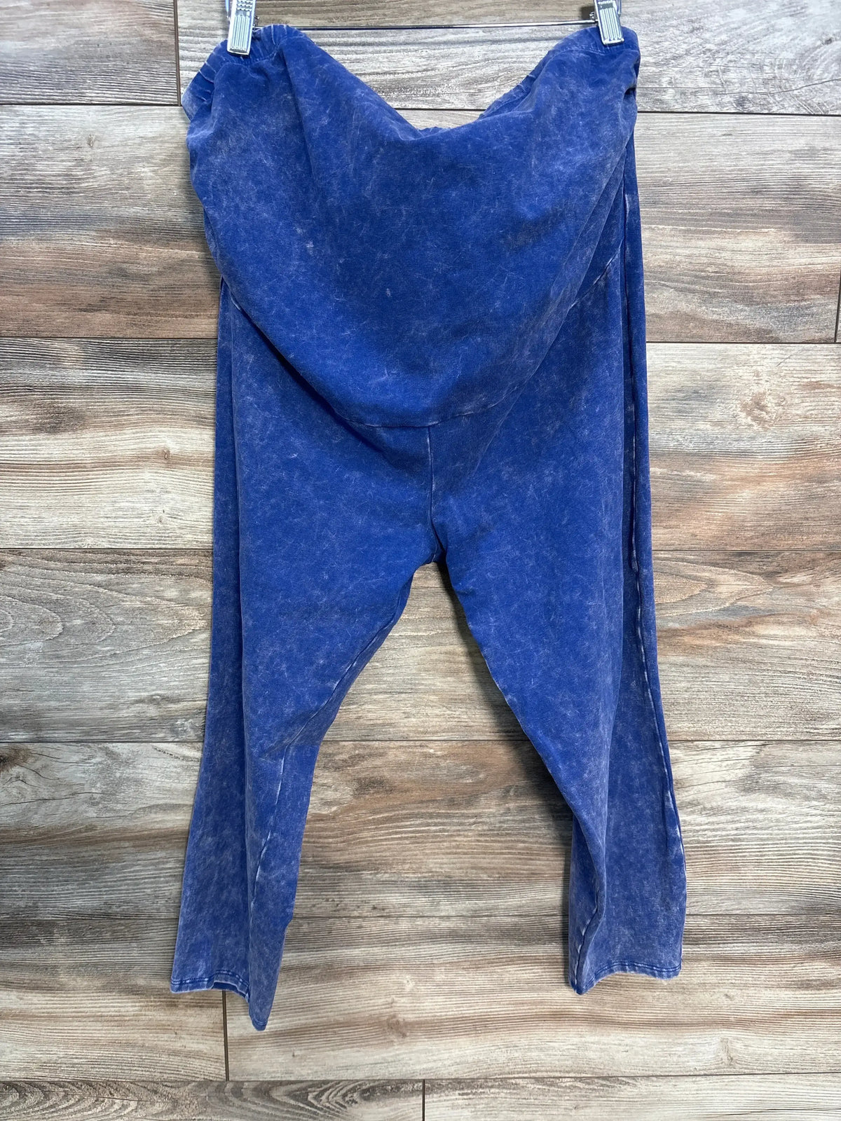 Front view of Torrid full-panel maternity pants in blue acid-wash with full belly panel and tapered legs against wooden wall