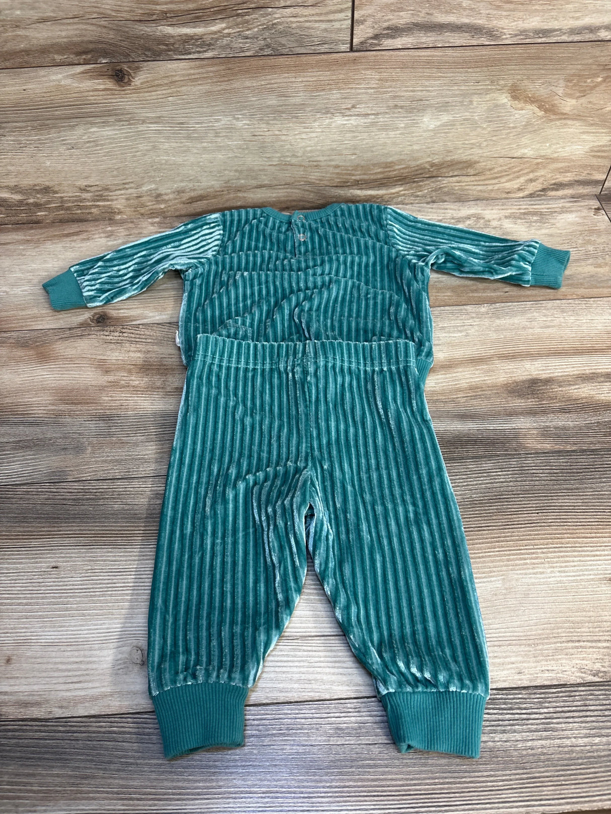 Teal ribbed velvet baby outfit with long sleeves and pants on wooden floor
