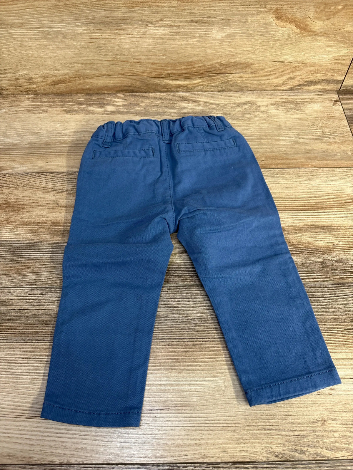 Back flat-lay of Children’s Place blue toddler pants, 12-18 months, elastic waistband and faux back pockets on wood background