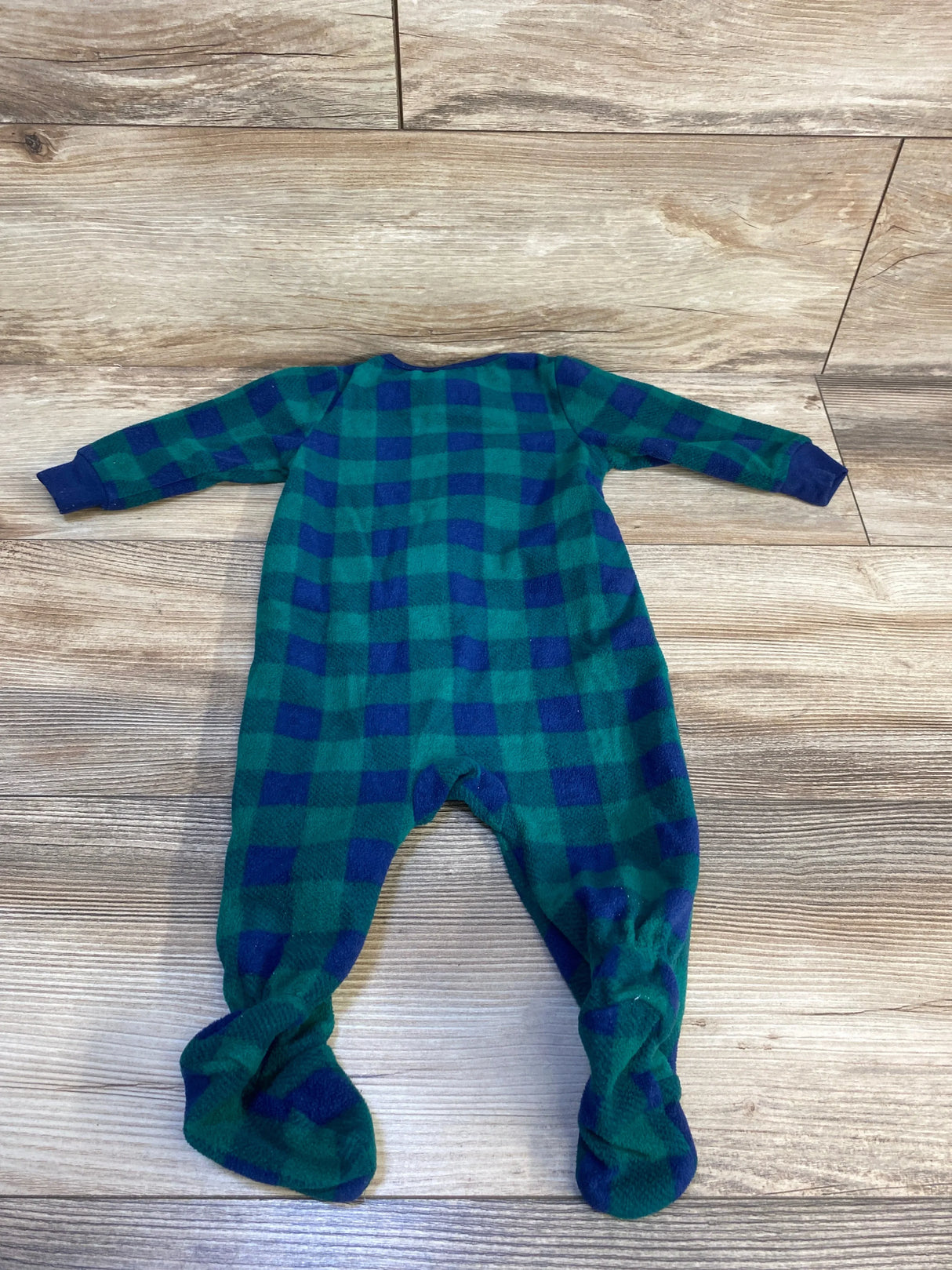 Green and navy plaid fleece baby footed sleeper on wood surface
