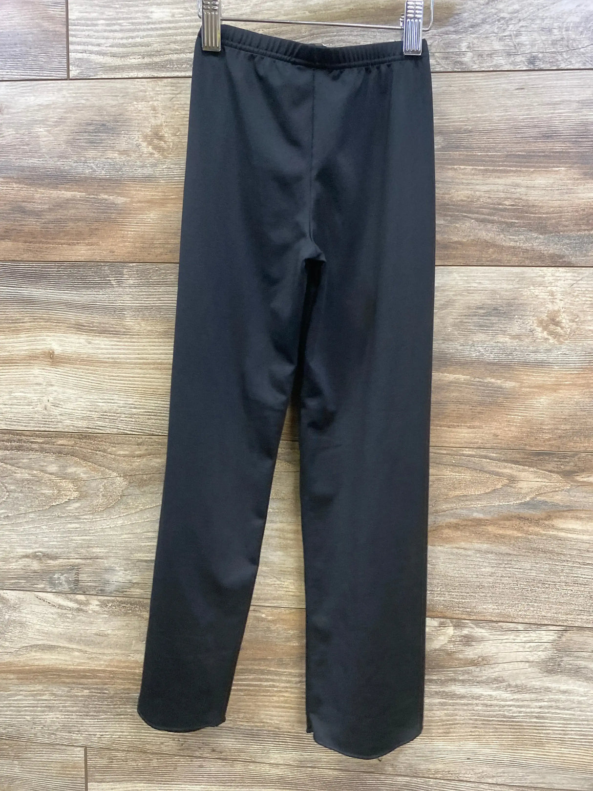 Front view of black Body Wrappers jazz pants, size 4-6 toddler, showing elastic waistband and straight legs on wood background