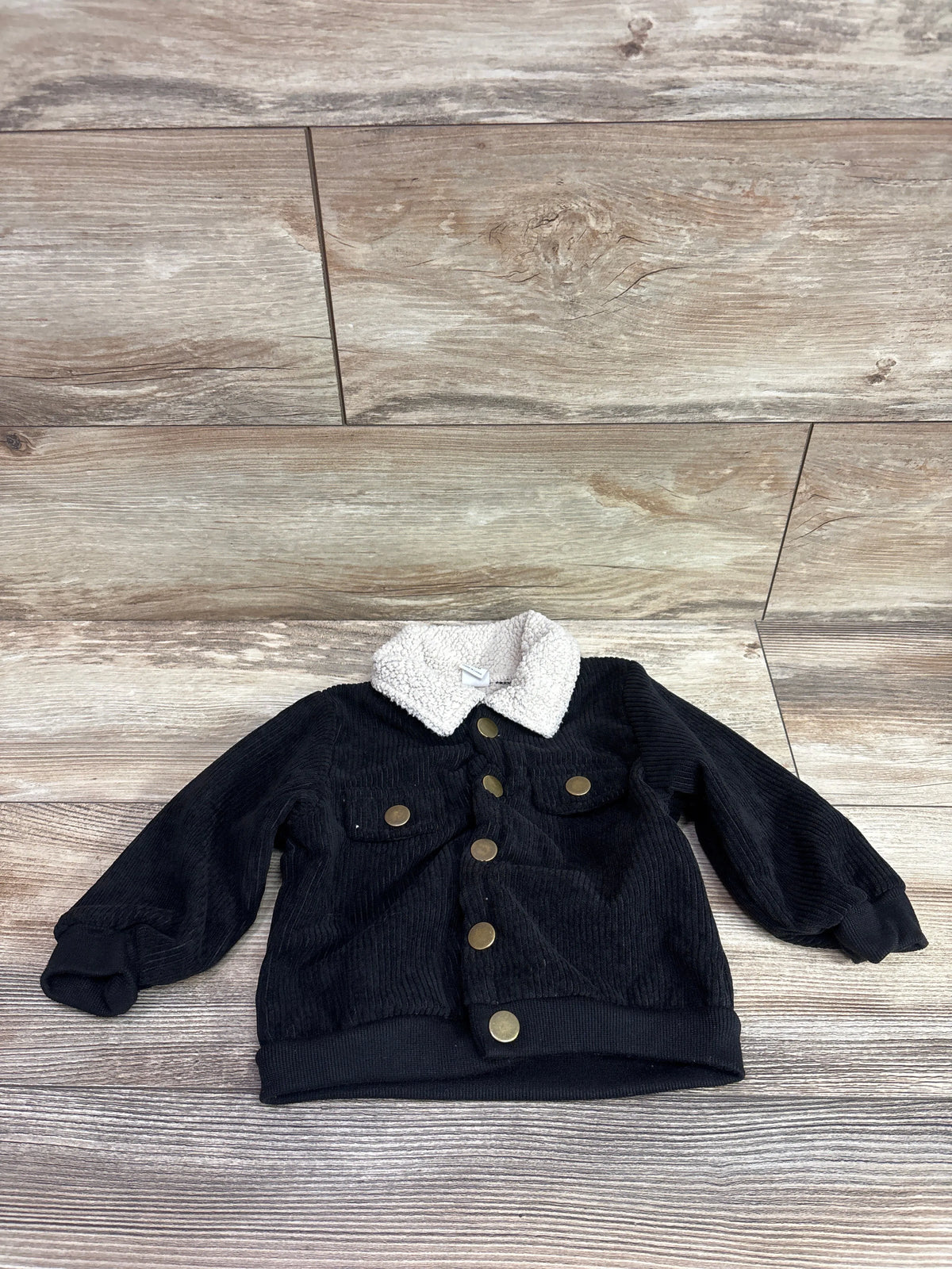 Shein black corduroy button-up baby jacket with a white sherpa collar on a wood background