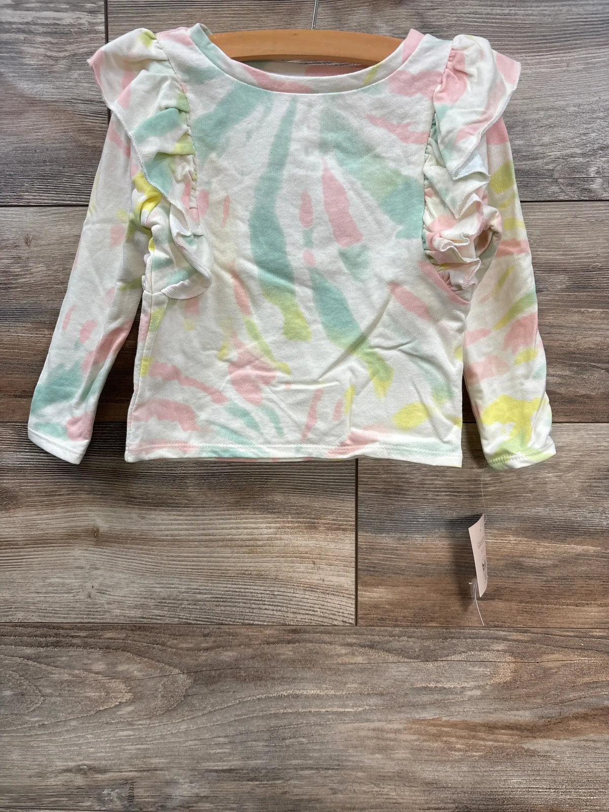 Pastel tie-dye long sleeve toddler shirt with ruffle details on shoulders on wooden floor