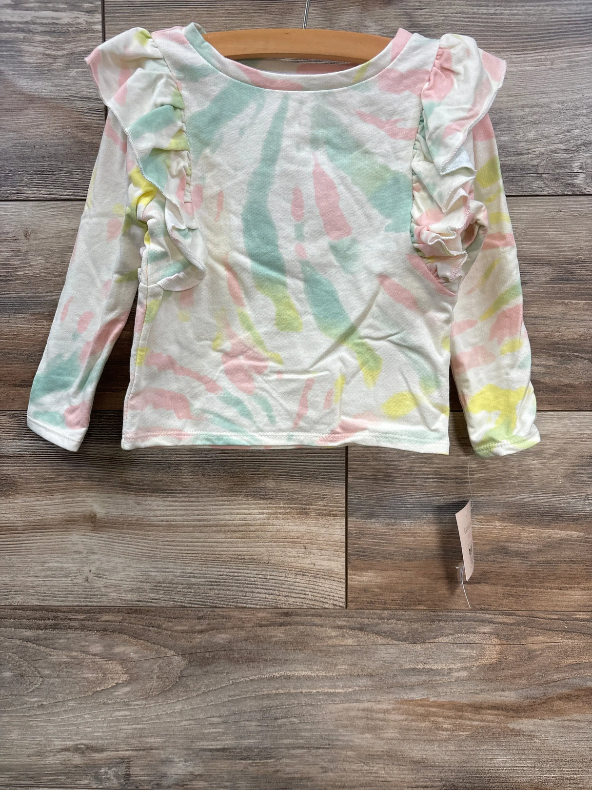 Pastel tie-dye long sleeve toddler shirt with ruffle details on shoulders on wooden floor