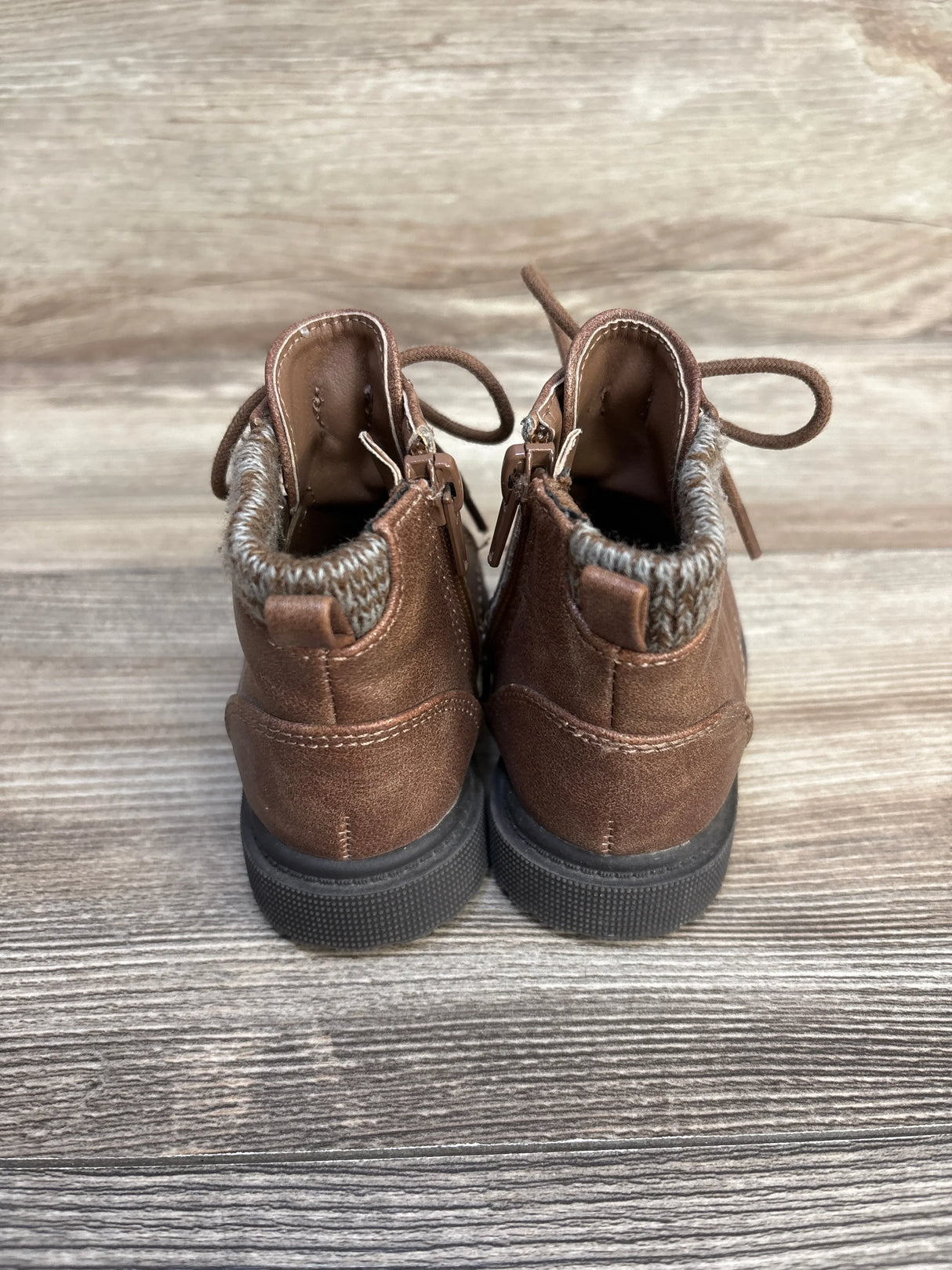 Brown toddler ankle boots with knit trim and side zippers on rustic wood background