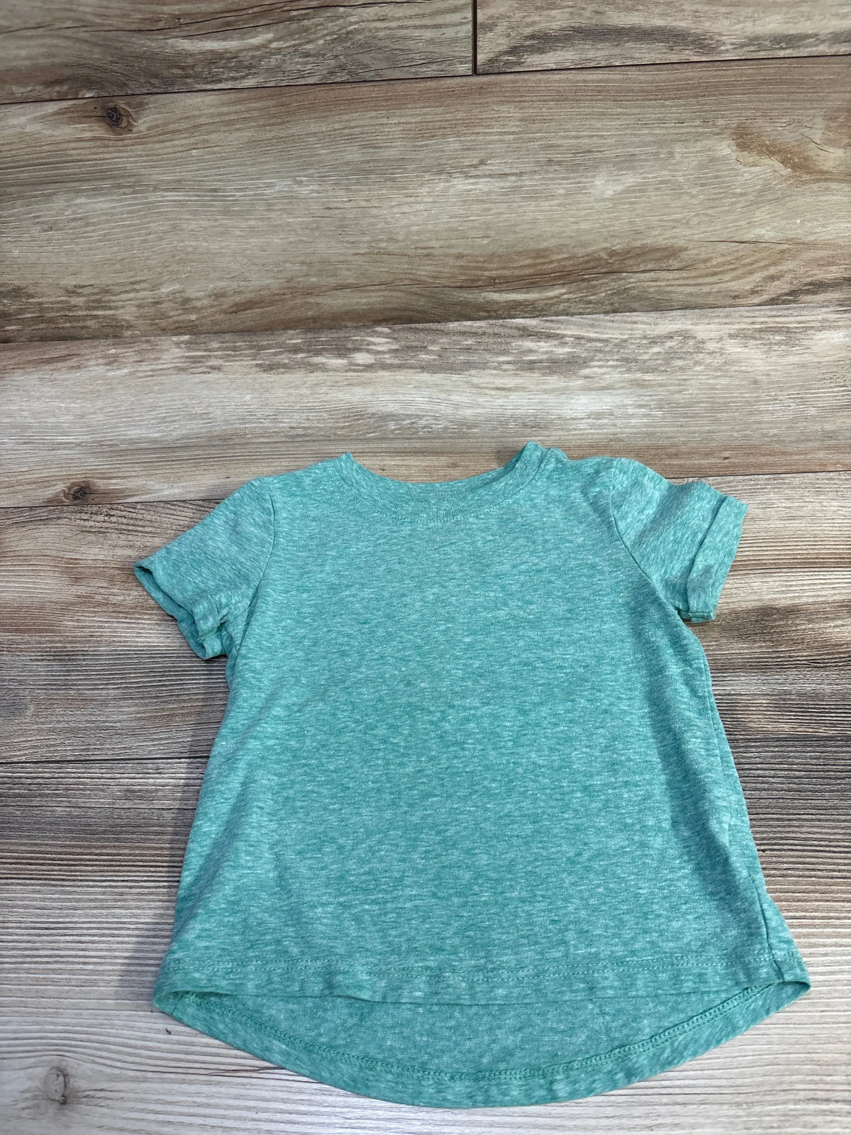 Front flat-lay of green heathered Cat & Jack toddler T-shirt showing short sleeves and curved high-low hem on wood background