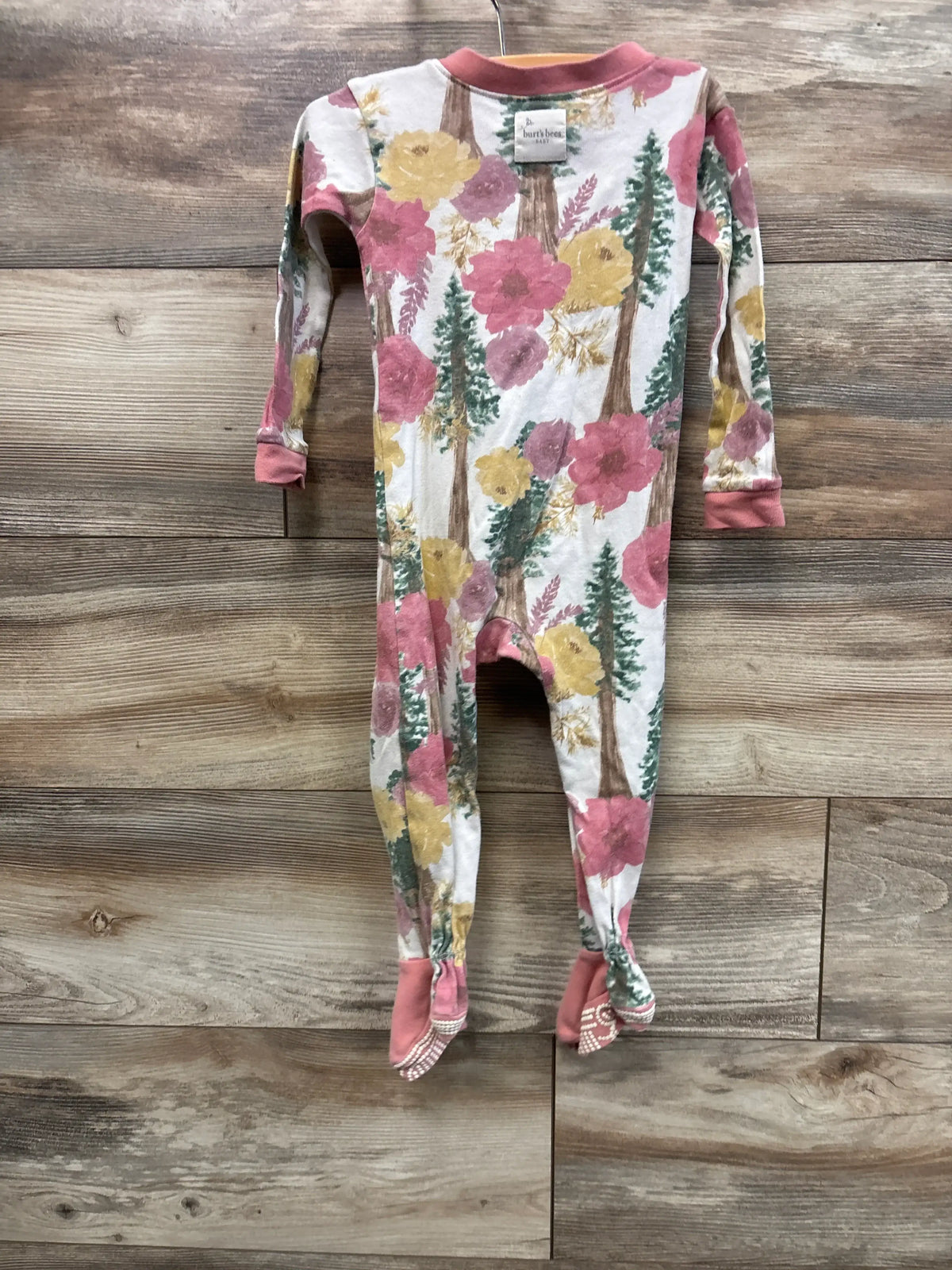 Front view of Burt’s Bees Baby pink floral sleeper, size 18 months, showcasing long sleeves and footed legs on a wood floor