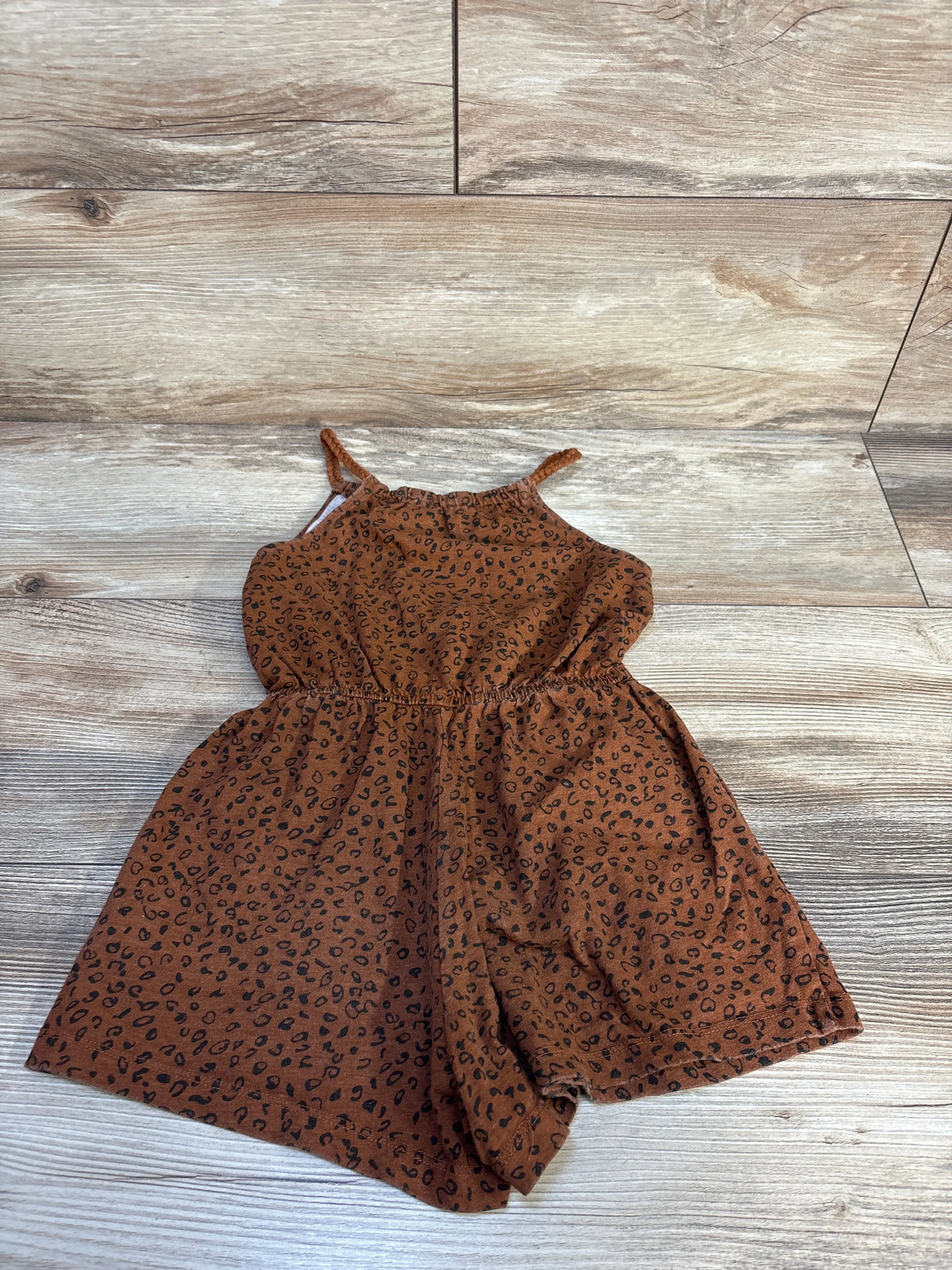 Brown leopard print toddler romper with spaghetti straps on wood background