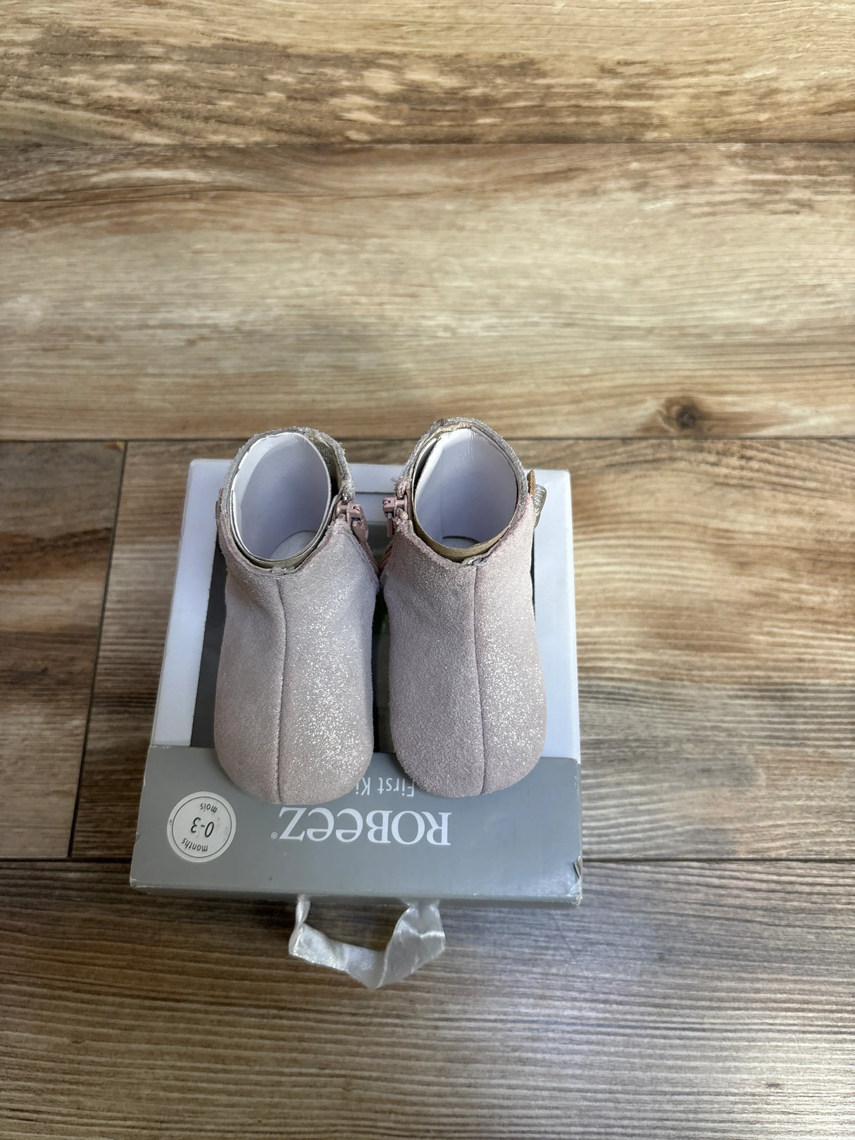 Back view of NEW Robeez First Kicks Madison Boots Pink sz 1/2c in shimmery pink suede with side zipper on original Robeez 0-3 month box on wood plank floor