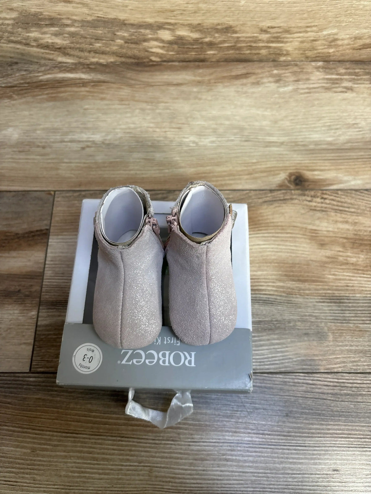 Back view of NEW Robeez First Kicks Madison Boots Pink sz 1/2c in shimmery pink suede with side zipper on original Robeez 0-3 month box on wood plank floor