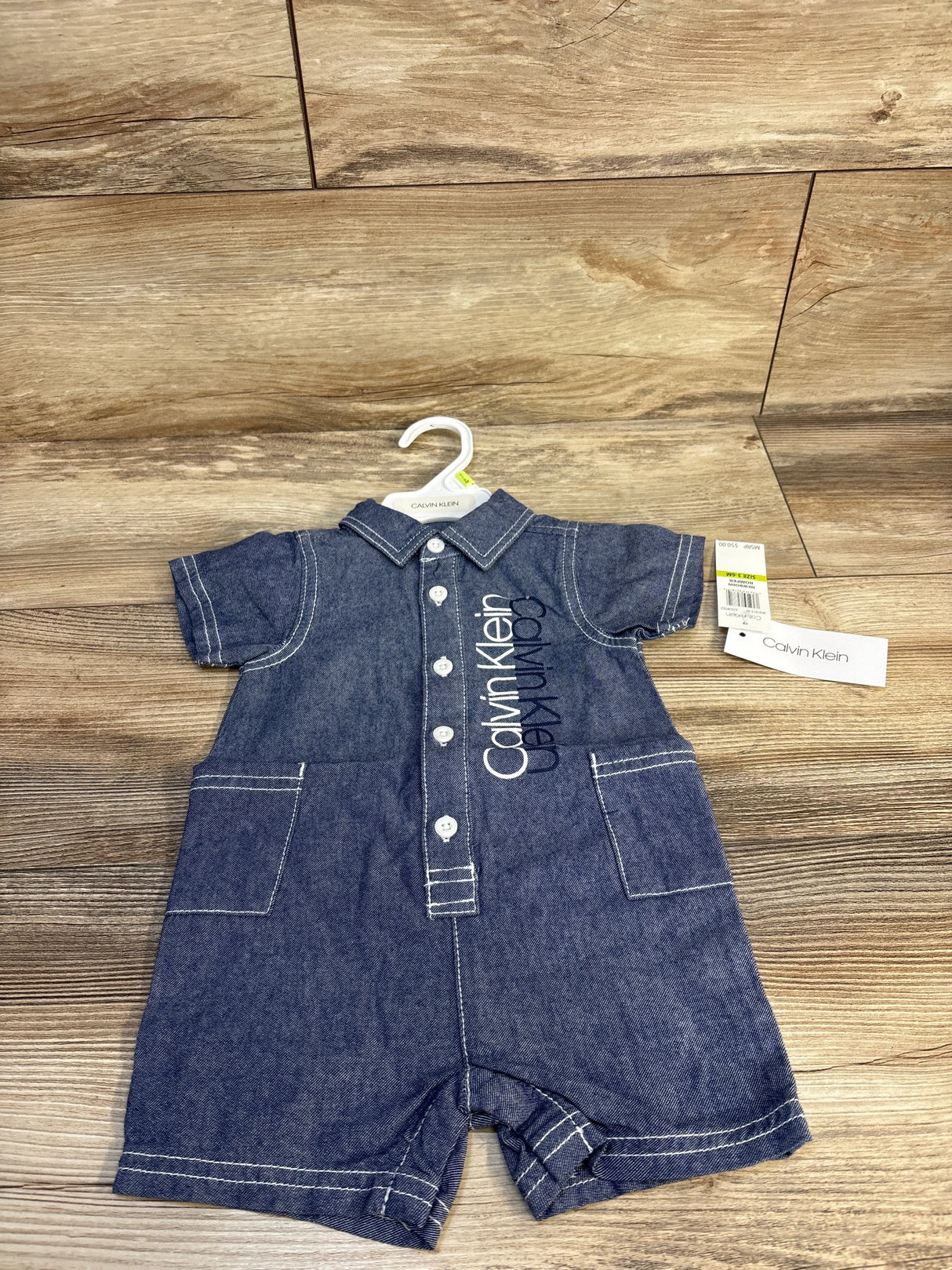 Denim short sleeve baby romper with buttons and front pockets, Calvin Klein logo visible.