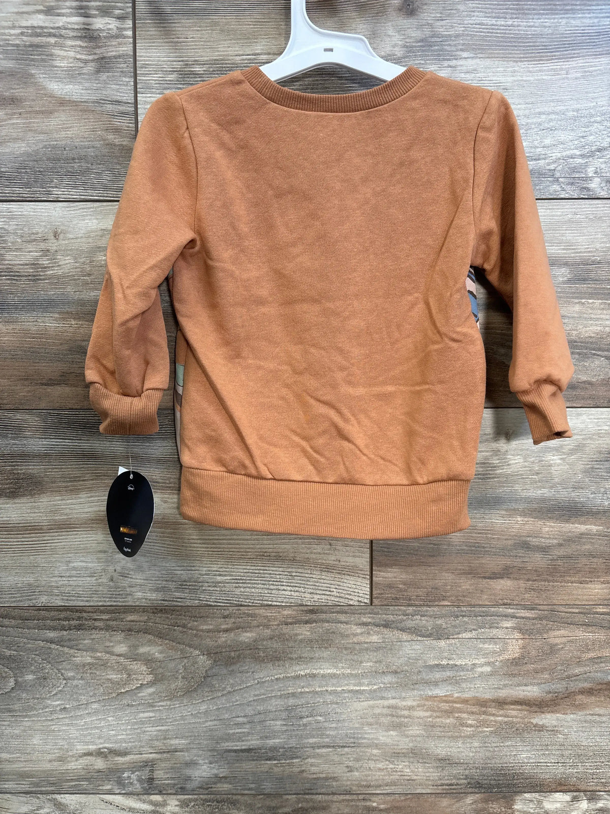 Front view of caramel Star Wars sweatshirt in size 2T with ribbed cuffs, collar, and hem on a wood-grain background
