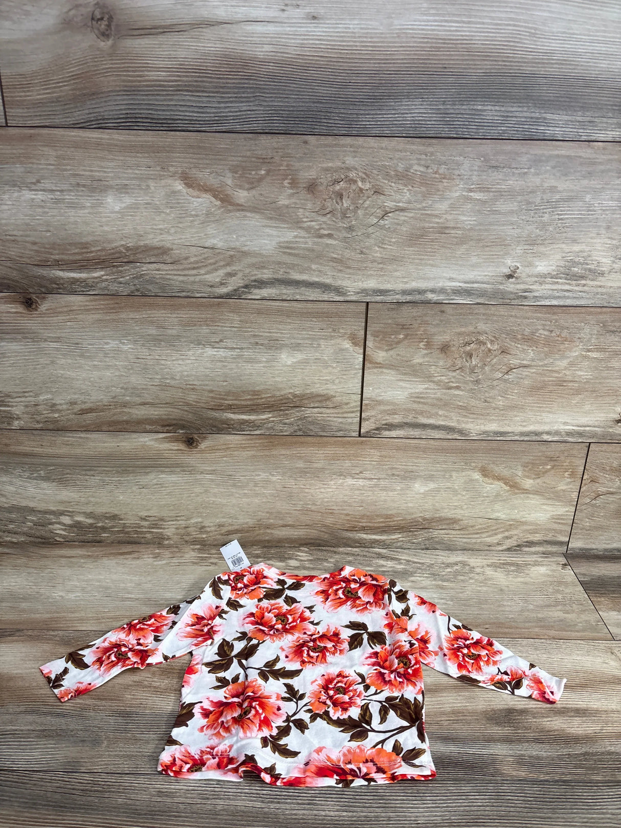 Long sleeve baby shirt with pink floral print on wood background, gently used kids clothing