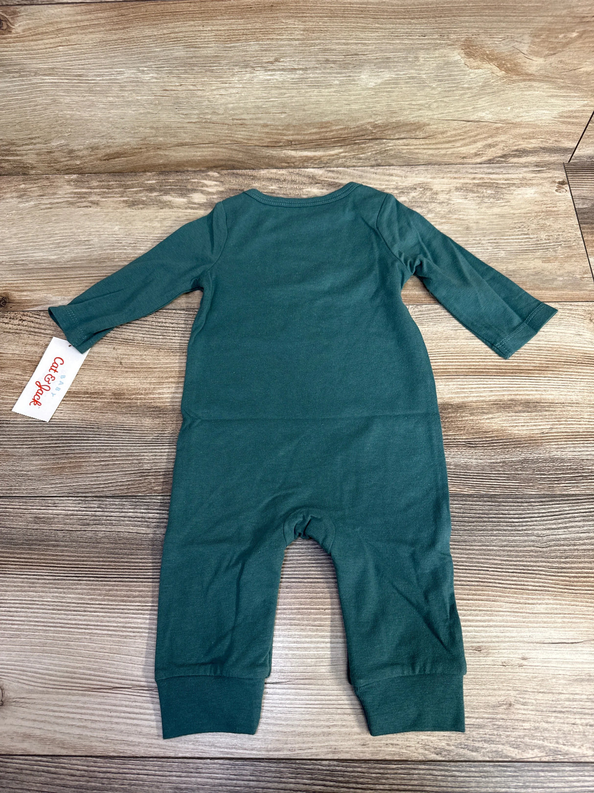 Teal green long-sleeve baby romper laid flat on wooden surface with tag visible