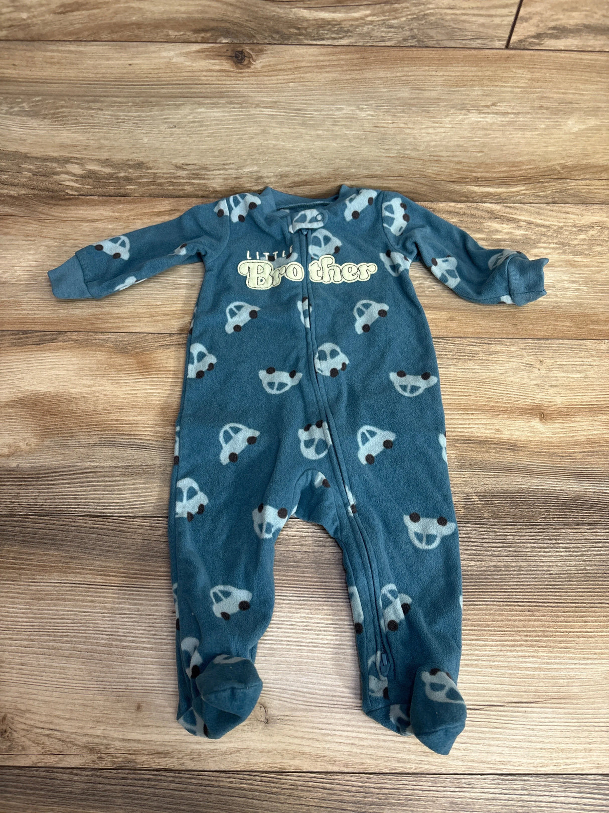 Blue footed baby sleeper with car print and 'Little Brother' text on wooden floor