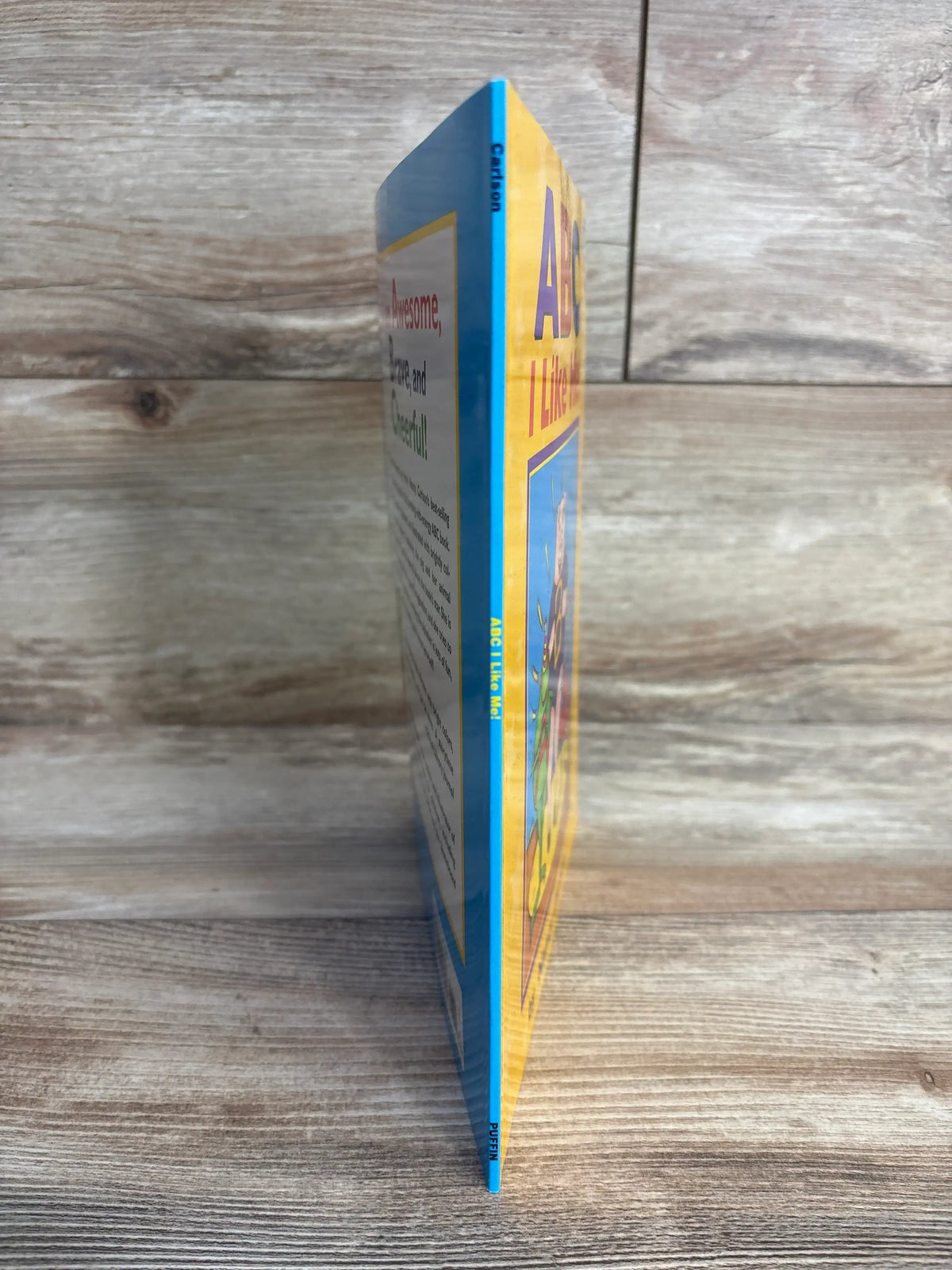 Side view of children’s book titled ABC I Like Me on wooden background