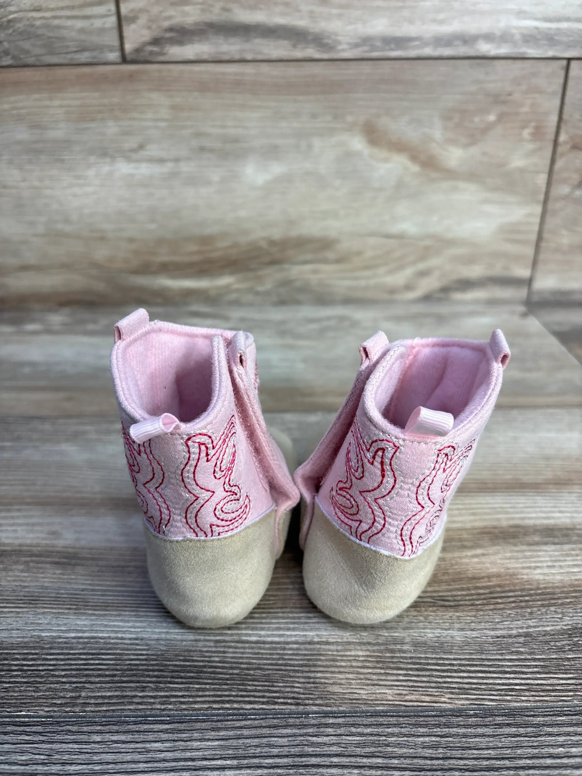 Pair of pink Stepping Stones cowgirl crib boots with red embroidery and tan soles.
