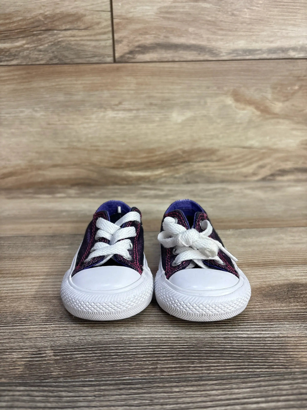 Purple toddler sneakers with white laces on wood floor background