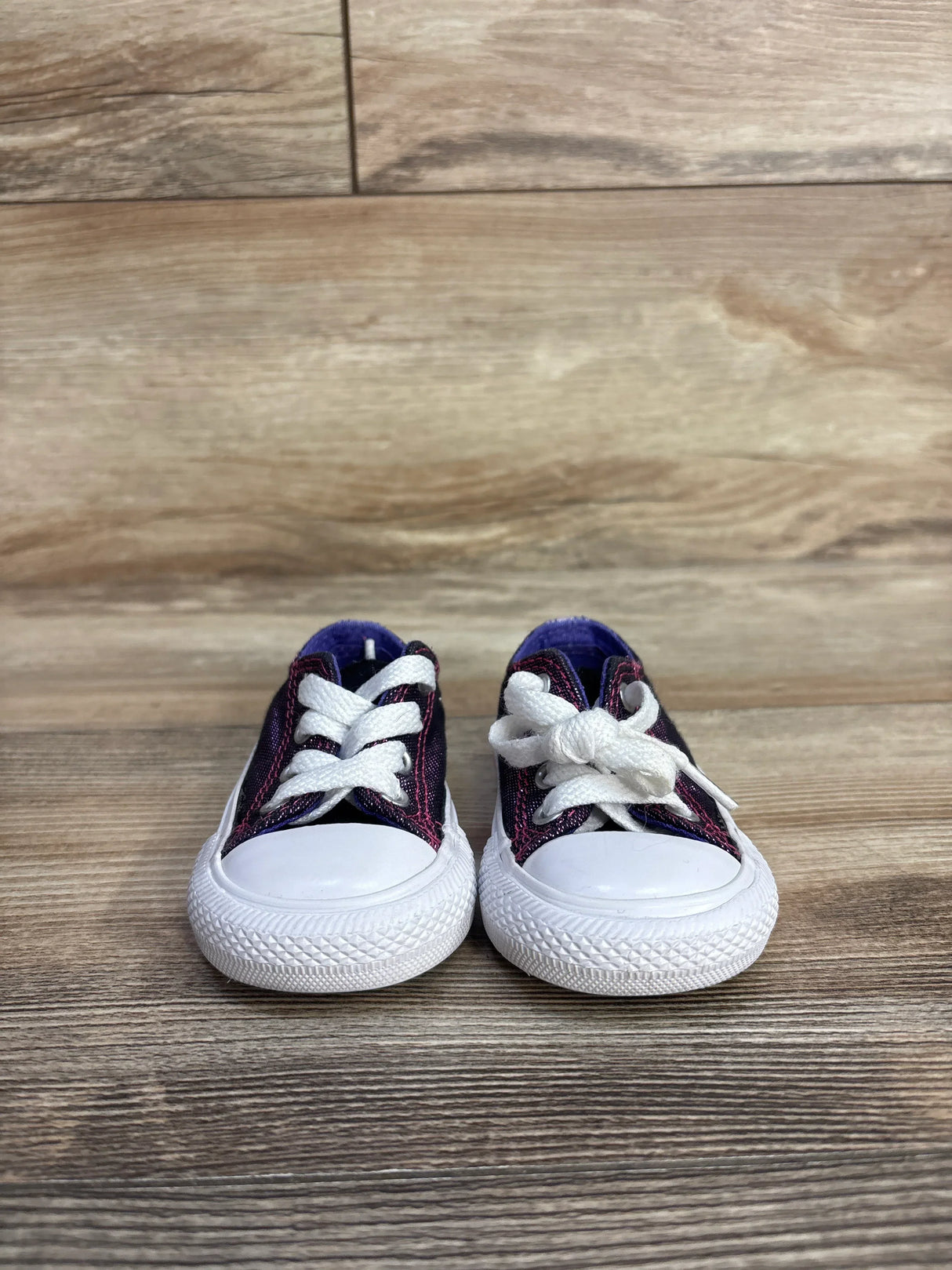Purple toddler sneakers with white laces on wood floor background