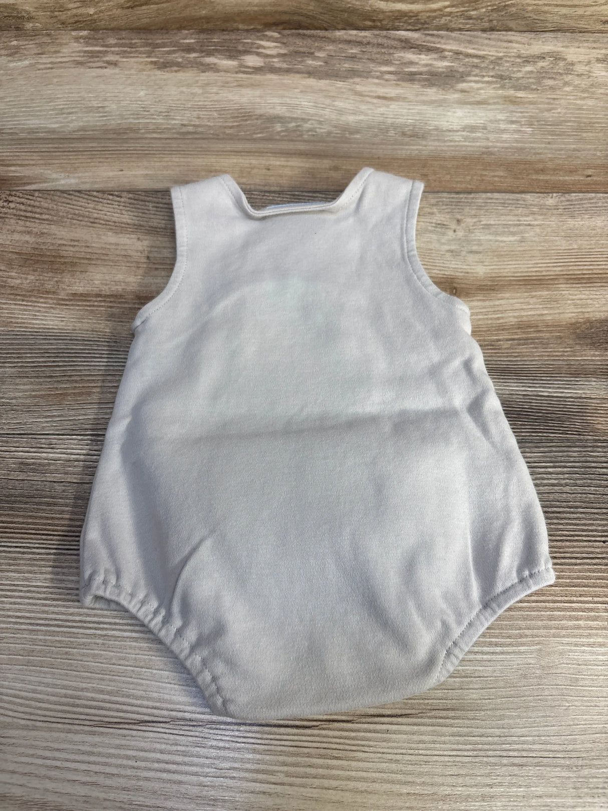 Top-down view of grey Three Sisters hippo bubble romper, sleeveless cotton baby romper with gathered elastic leg openings on wood background