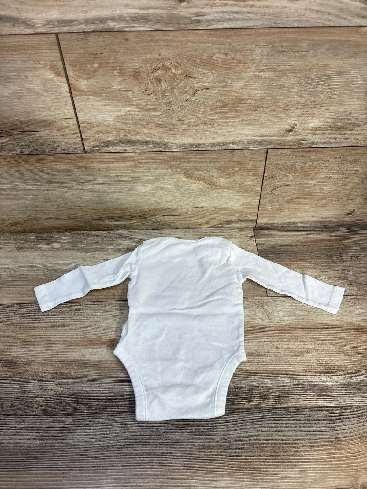 Front view of Old Navy My First Halloween bodysuit in white, size 3-6 months, showcasing long sleeves on a wood floor