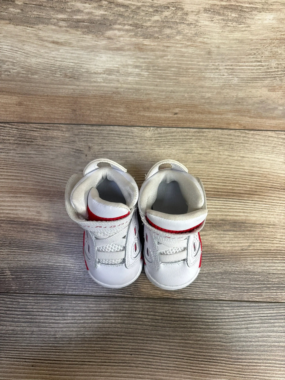 Top-down view of Air Jordan 6-17-23 TD White/University Red toddler sneakers size 3C with Velcro strap closure and red accents on wooden floor
