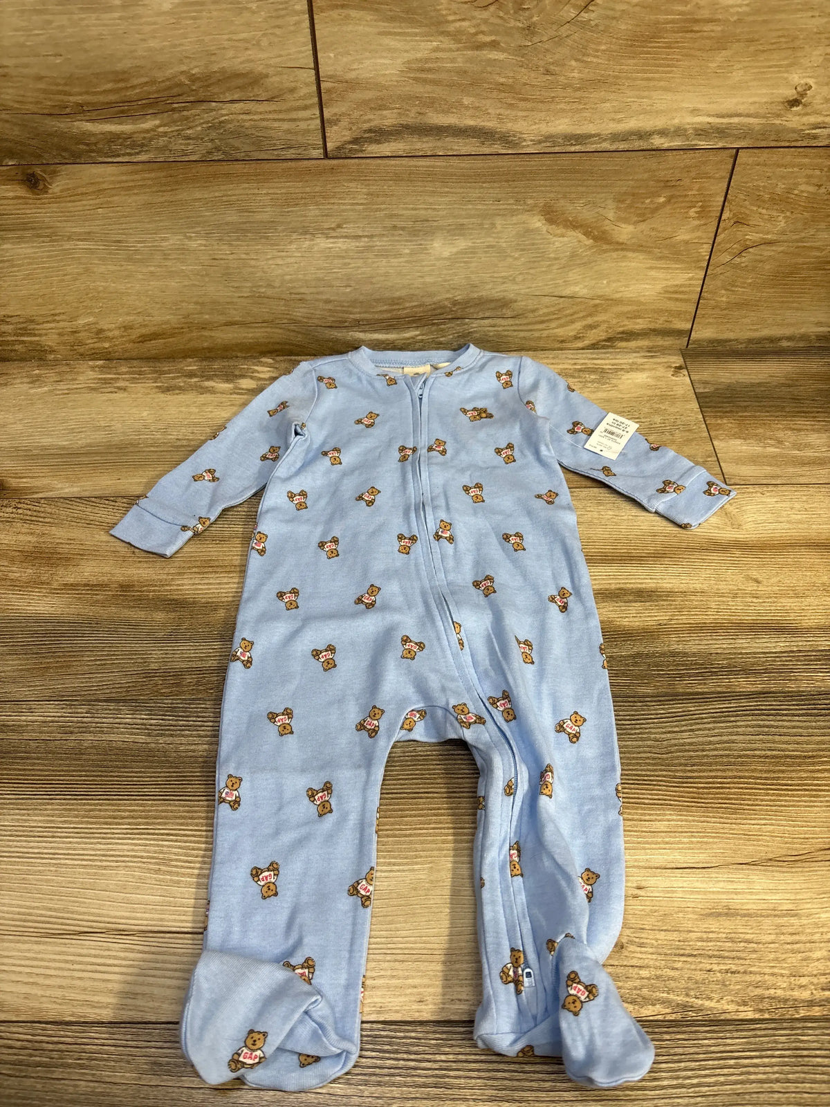 Front view of Baby Gap blue bear print sleeper showcasing full-zip design and footed legs on a wood background