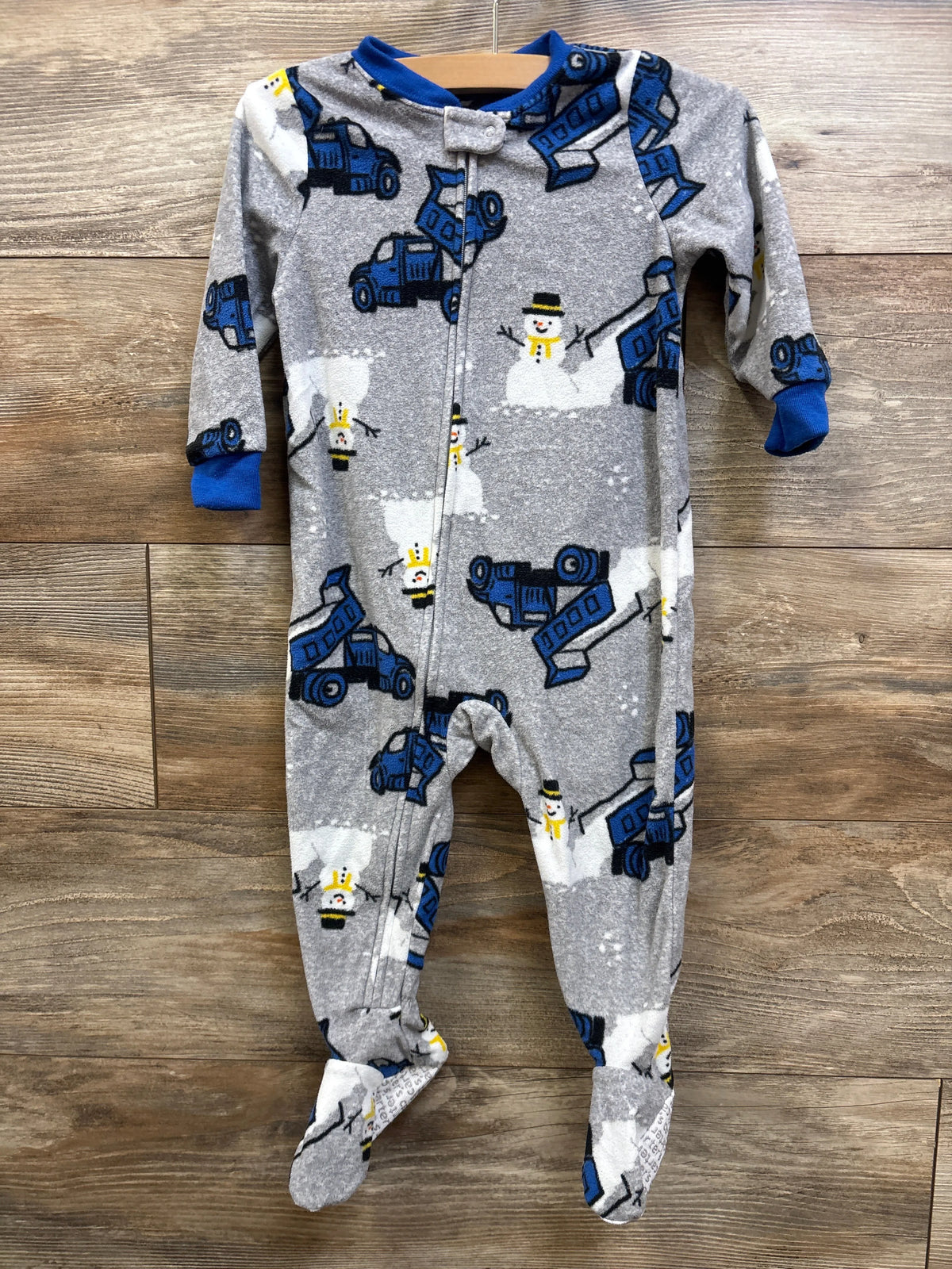 Front view of Carter’s grey blanket sleeper, size 18 months, showcasing construction vehicle and snowman print on wood