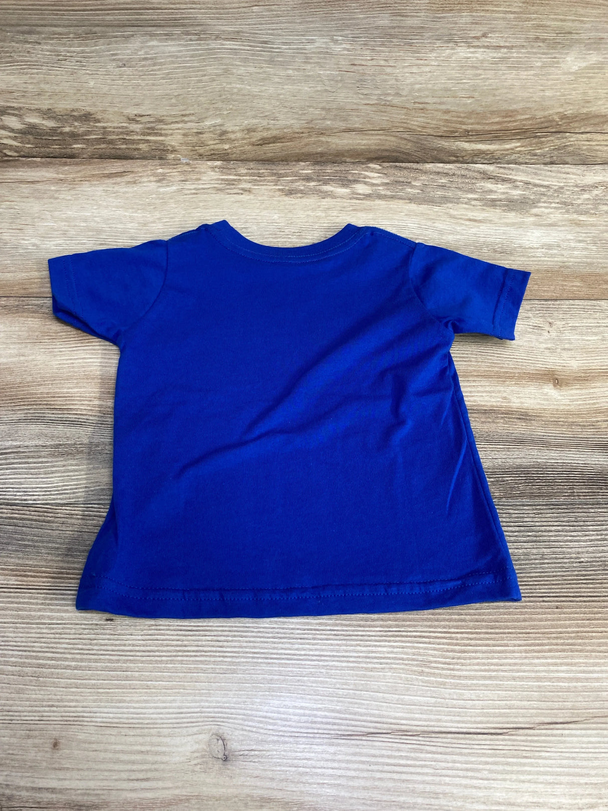 Back view of royal blue Rabbit Skins baby t-shirt size 12M showing short sleeves and crew neck on wood background