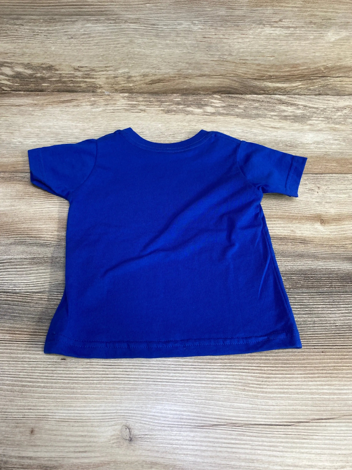 Back view of royal blue Rabbit Skins Rawrrr In The USA shirt sz 12m showcasing short sleeves and plain back on wood plank floor