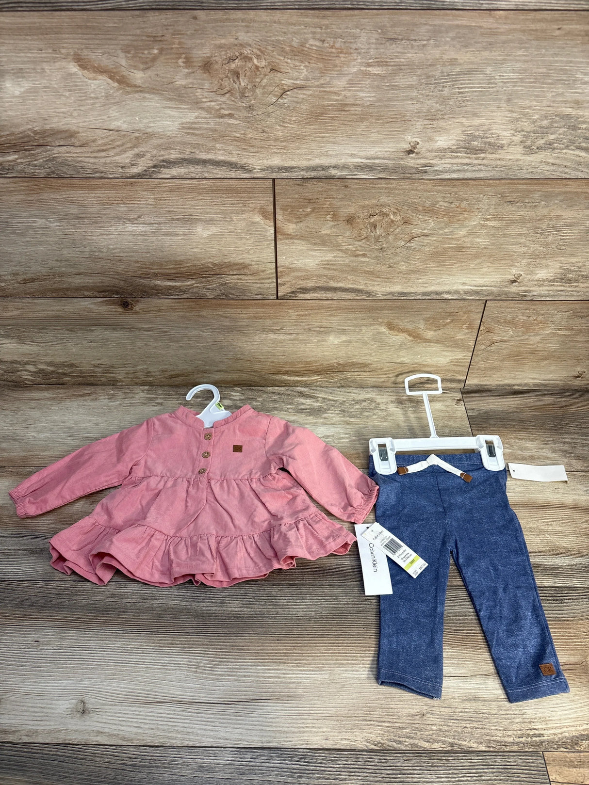 Calvin Klein baby girl outfit with pink long-sleeve dress and blue leggings on wooden floor