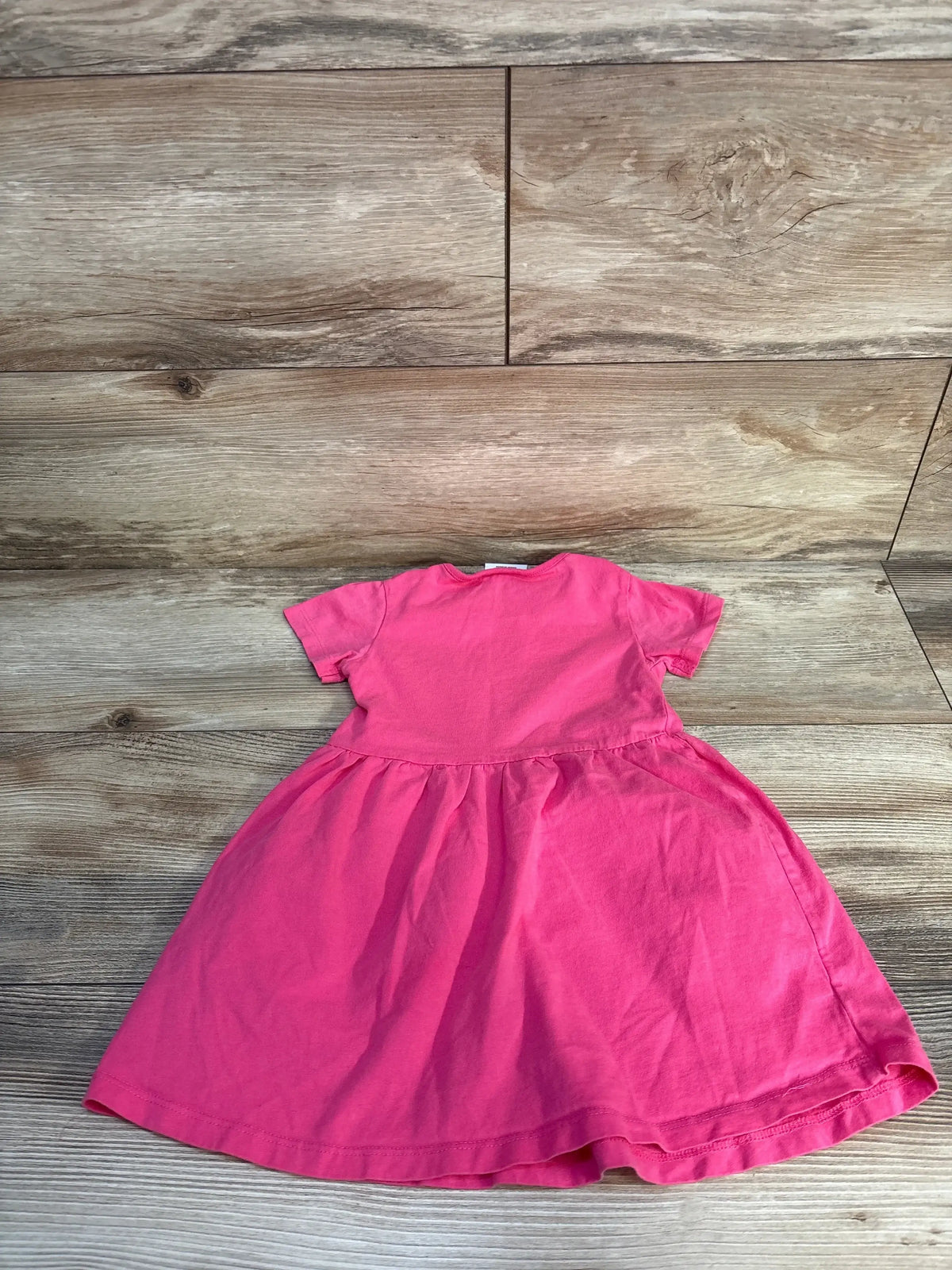 Back view of hot pink Peppa Pig Sunshine Vibes toddler dress, 18-24m, short sleeves and gathered skirt on wood background