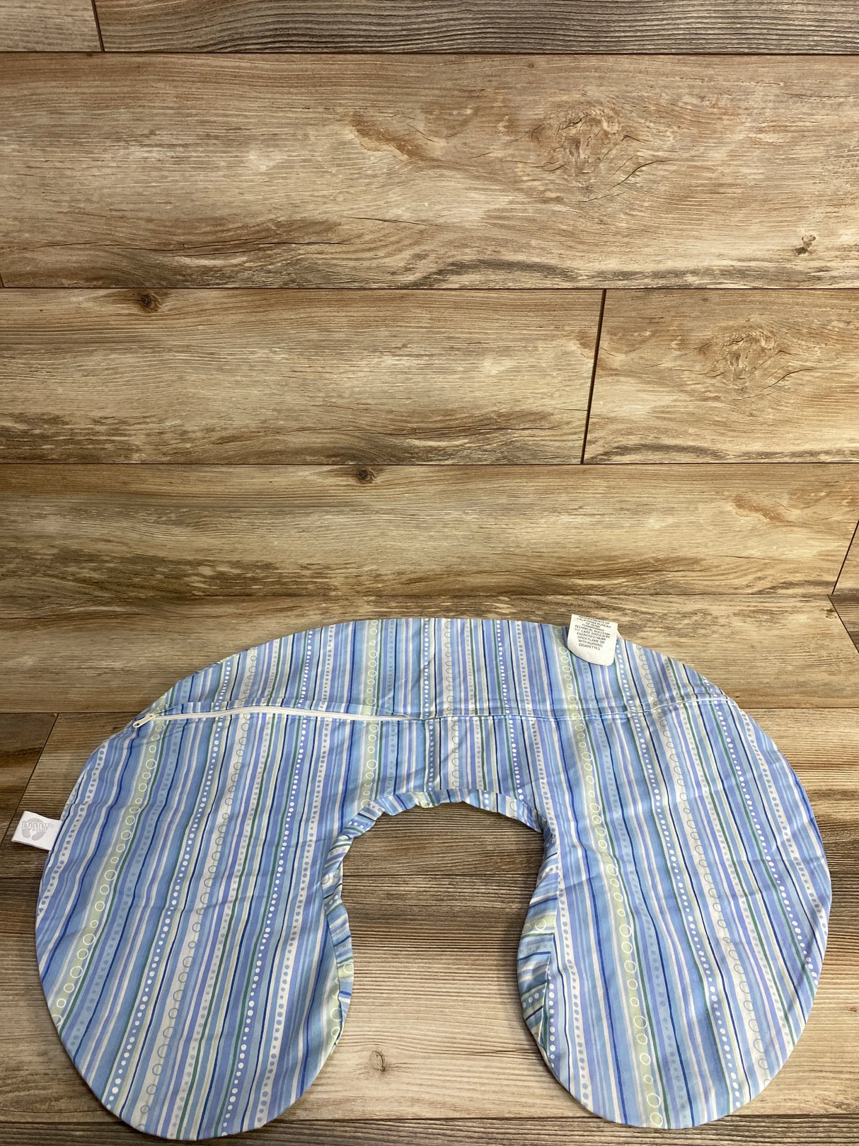 Top-down view of Boppy nursing pillow cover showing blue and green stripes and exposed zipper on wooden floor