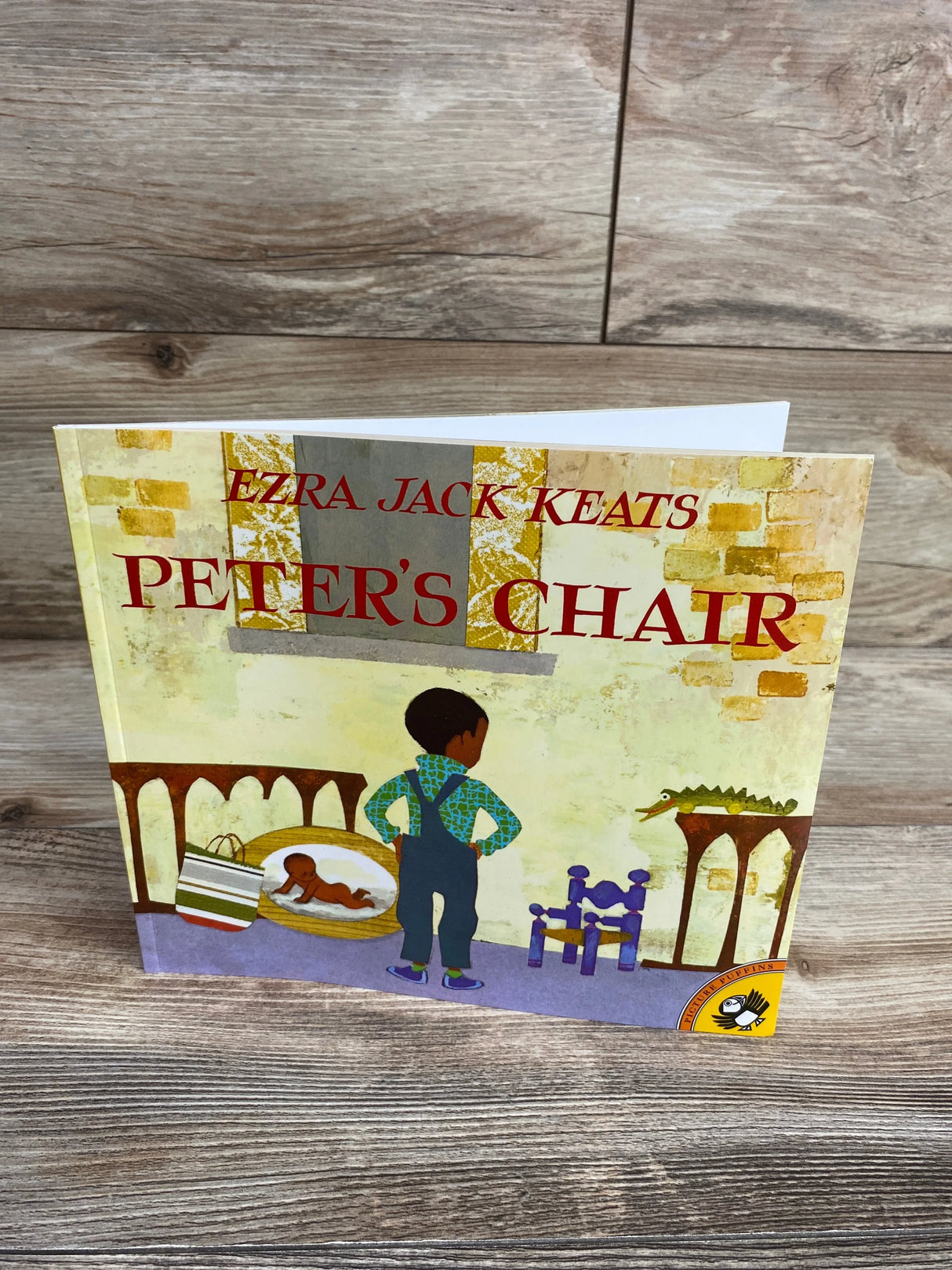Cover of Ezra Jack Keats' children's book Peter's Chair featuring a boy standing in front of a small purple chair and alligator toy